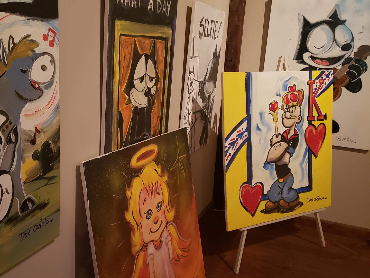A wall full of paintings of Felix the Cat, Popeye, and an angel