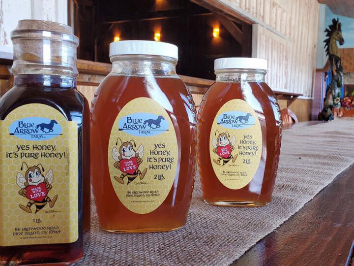 Jars of Blue Arrow honey lined up neatly on a table