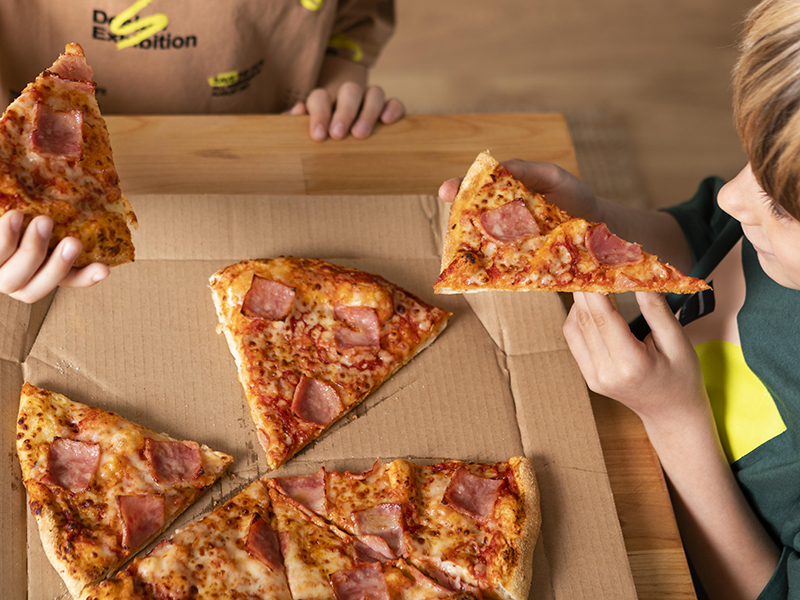 A box of pizza with two kids reaching in and each grabbing a slice